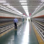 A worker walks through a wide hallway in an industrial textile plant, India.